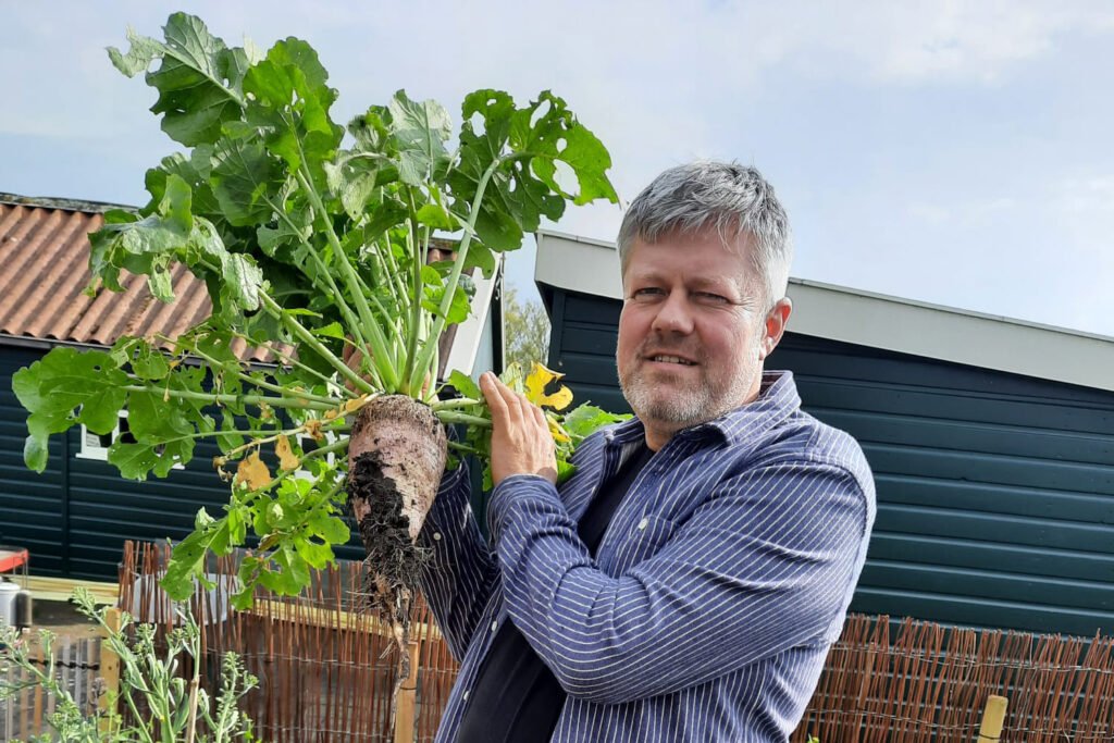 Peter Bouman met een radijsplant in de tuin